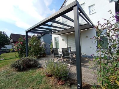 Überdachte Terrasse mit Glasdach und gemütlicher Sitzgruppe