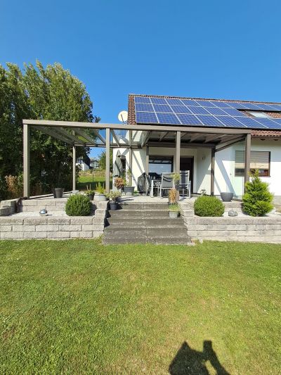 Terrassenüberdachung mit Glasdach und offener Gartenansicht