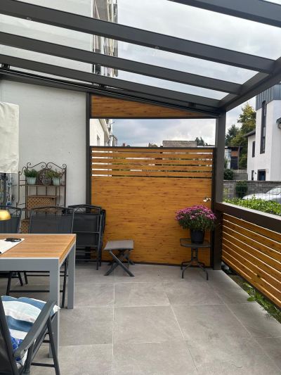 Terrassenüberdachung mit Glasdach und seitlichem Wetterschutz