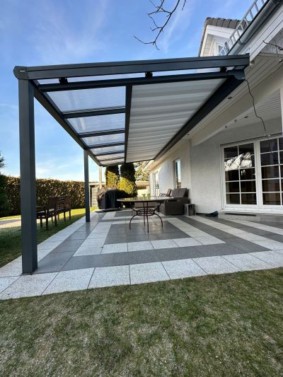 Terrassenüberdachung an Hauswand mit transparentem Dach und Unterglasmarkise