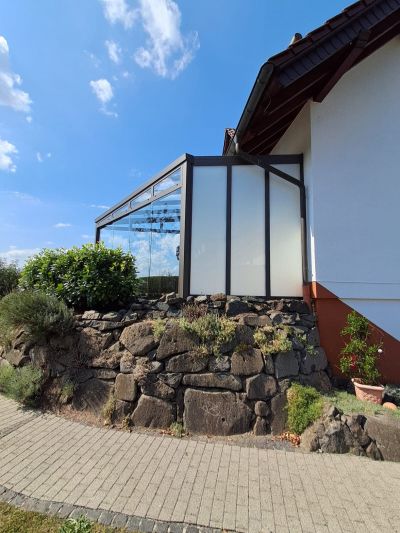 Geschützter Terrassenraum mit Glaswänden und Aluminiumrahmen